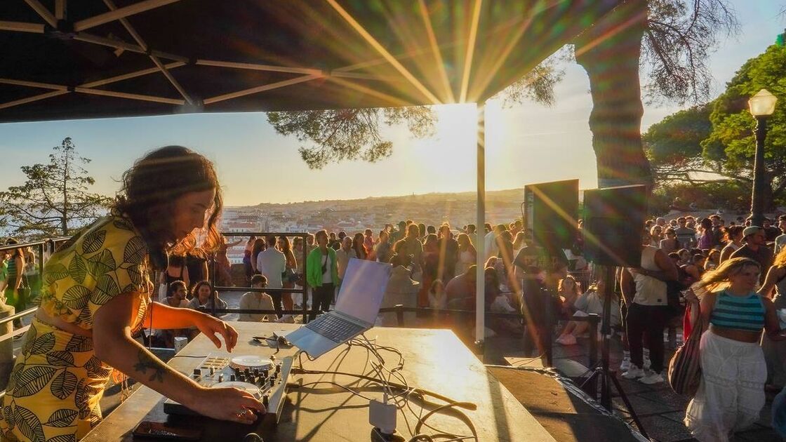 DJ atua para uma multidão ao ar livre, com vista para Lisboa