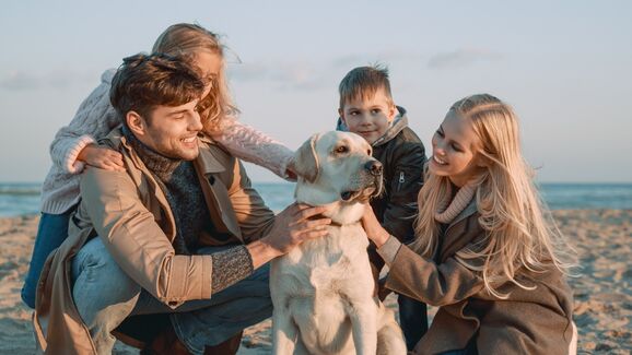 família com cão na praia