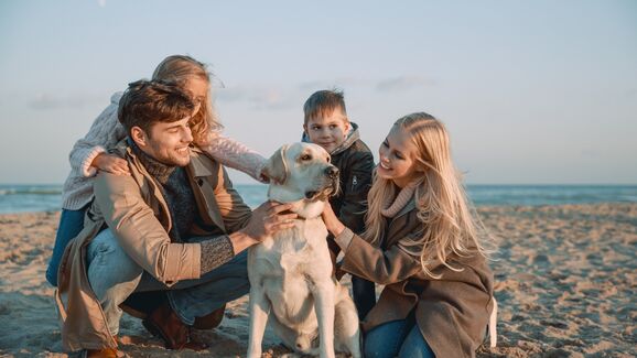 família com cão na praia