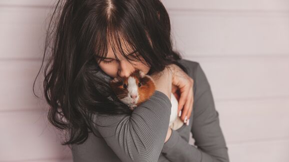 Mulher demonstra afeto por um porquinho-da-índia, realçando a ternura dos animais de estimação em espaços pequenos